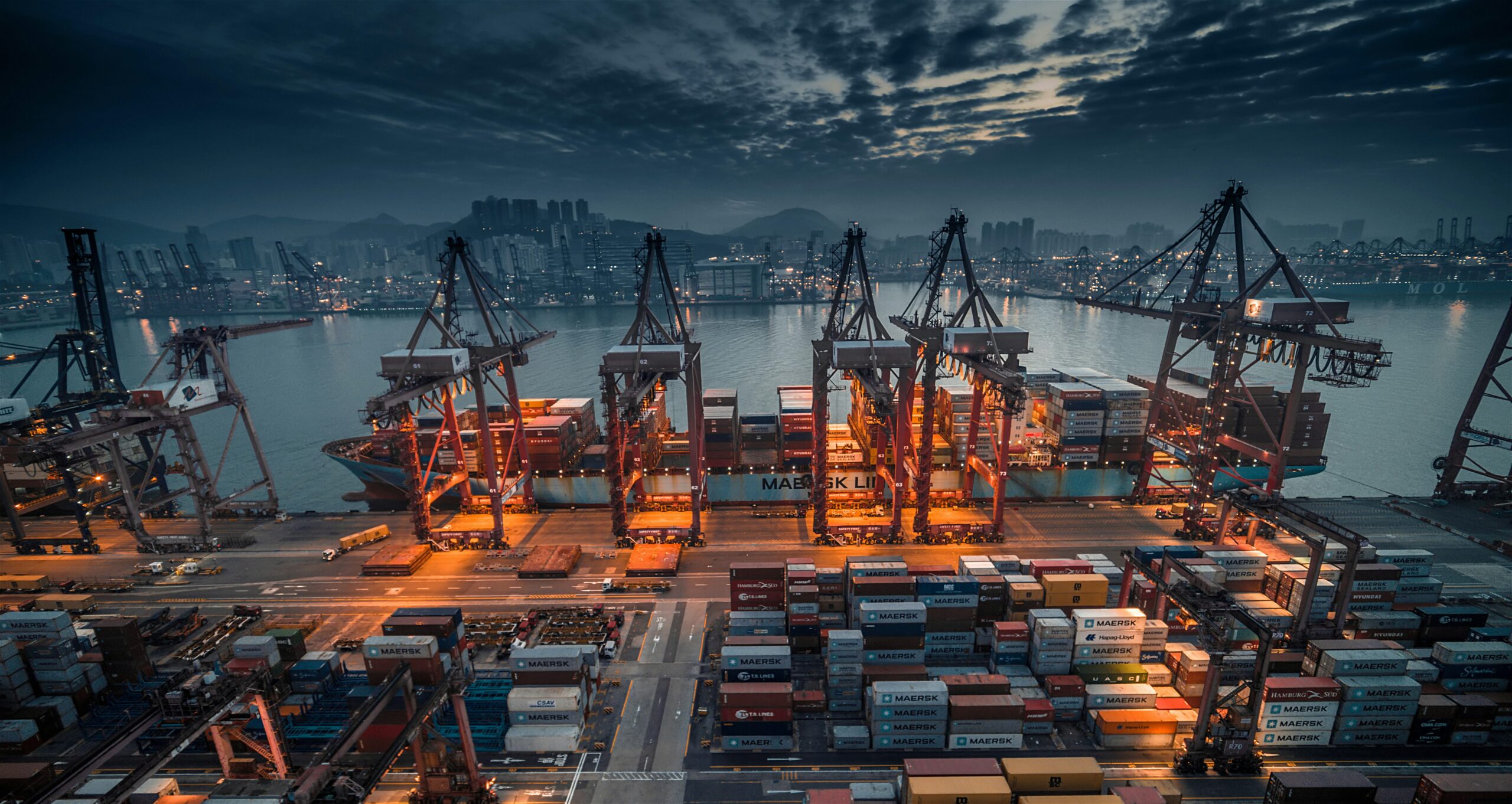 Shipyard lit at night filled with shipping containers